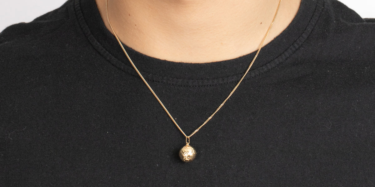 Goldene Halskette mit Fusßball-Anhänger am Dekolleté getragen