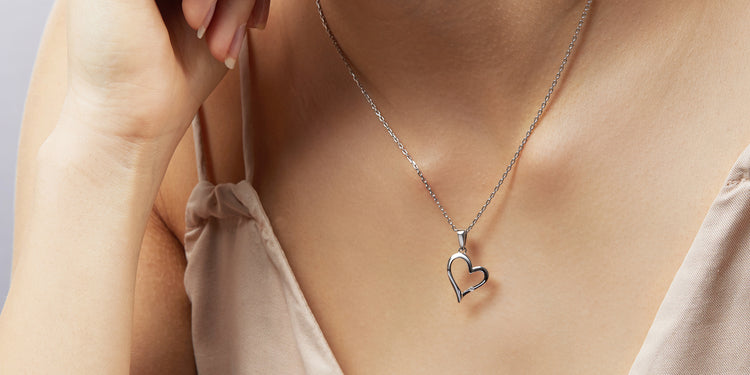 Silberne Halskette mit Herzanhänger am Dekolleté getragen